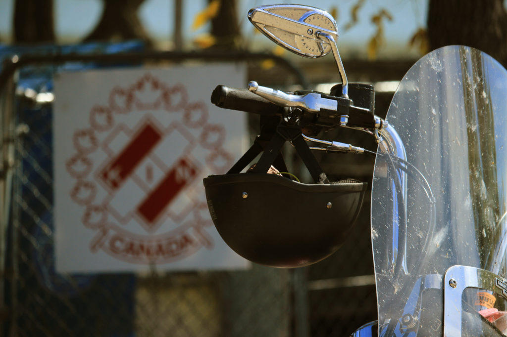 A helmet dangles from a handlebar; in the background, slightly blurred, is the Kin Canada logo